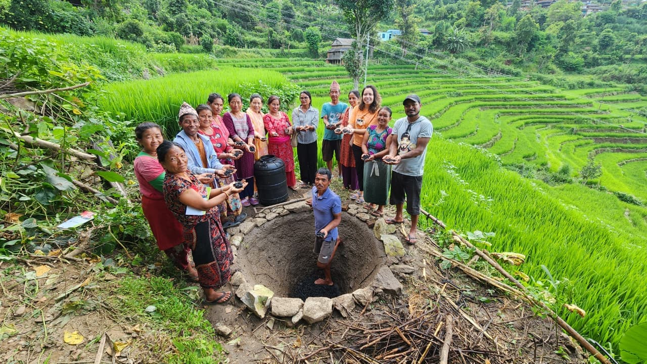 Community members and farmers in Dhading holding biochar soil during a field workshop